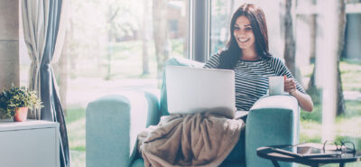 a woman sitting on a couch with a laptop.